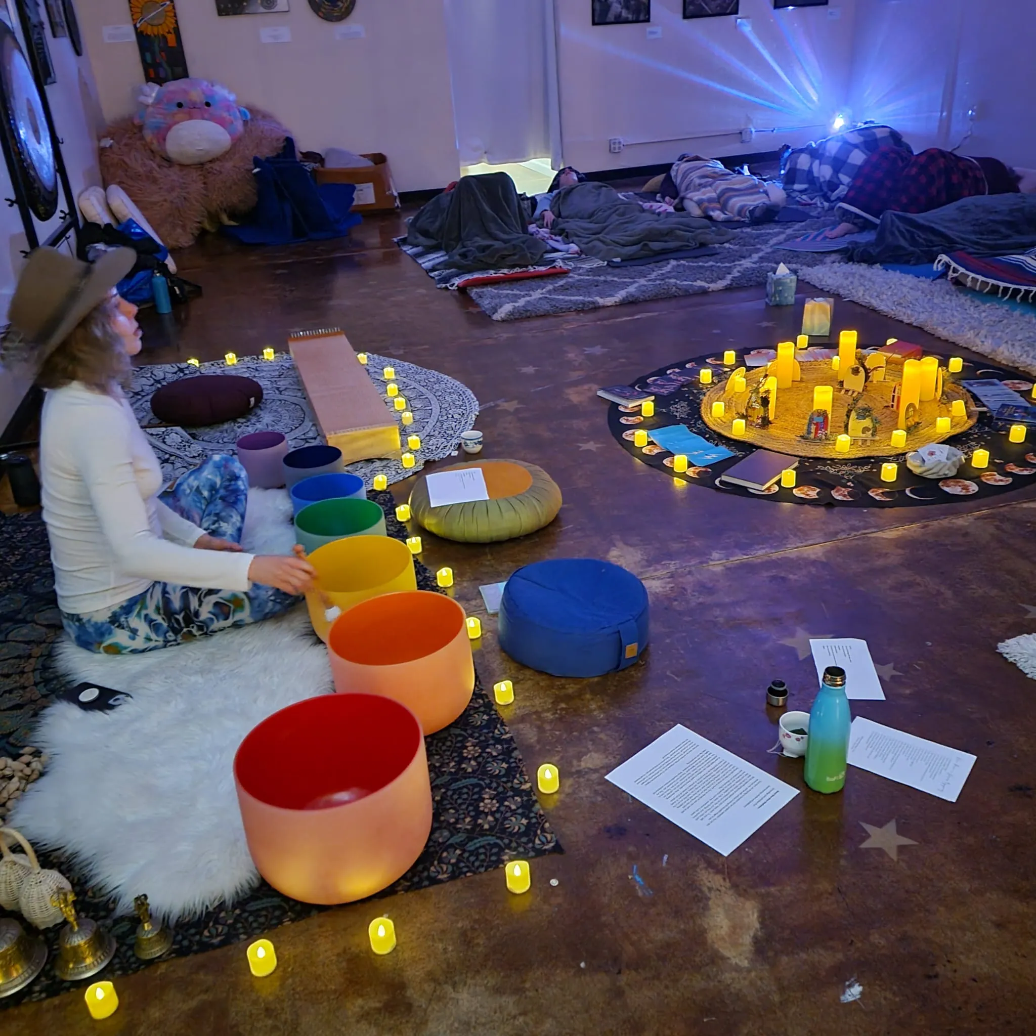 A curated sound healing space with colorful crystal singing bowls and candlelight