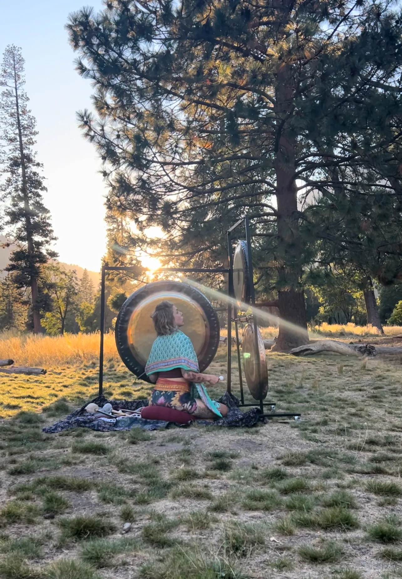 LeeAnna playing gongs outdoors at sunset in a meadow