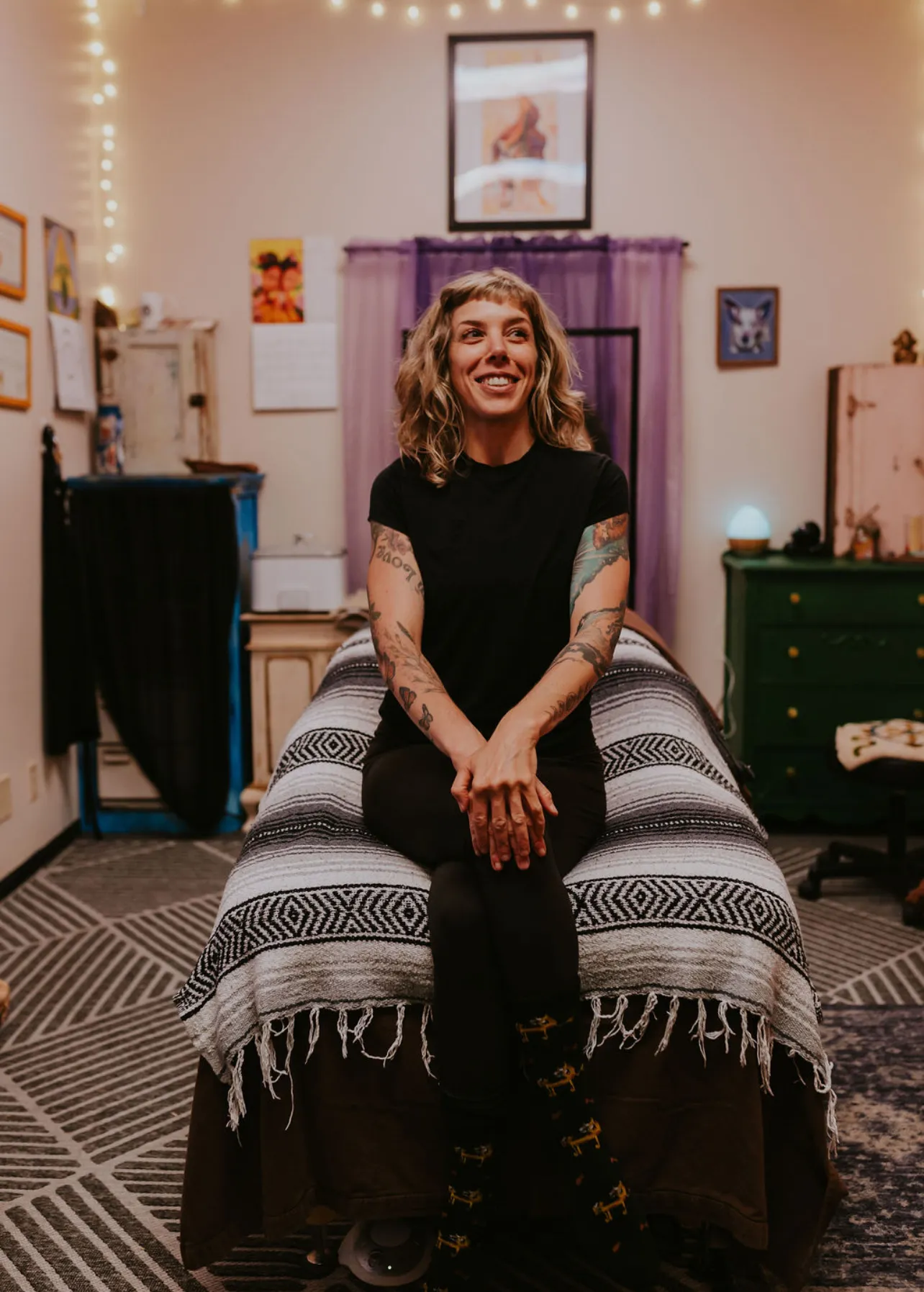 LeeAnna seated on a massage table in her studio
