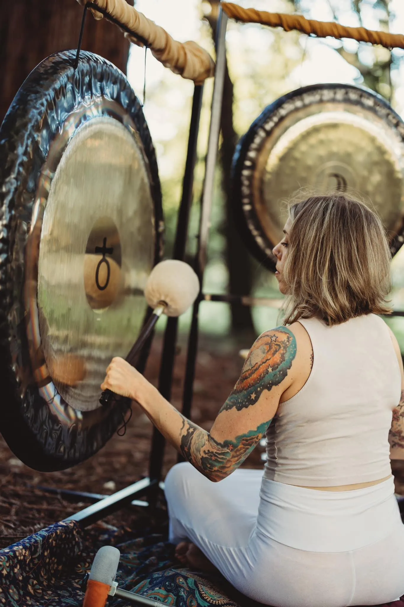 LeeAnna playing gongs in a forest setting