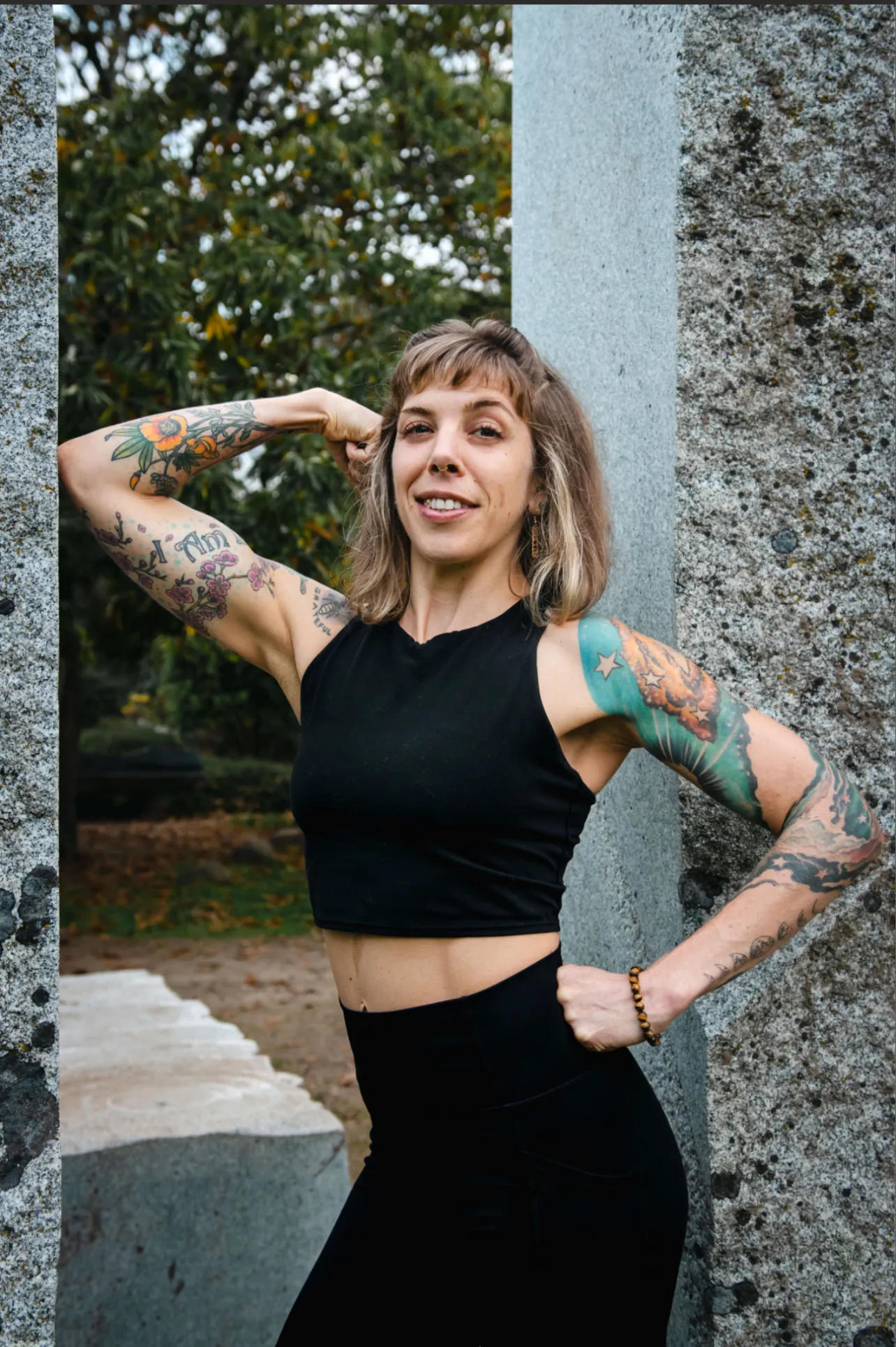 LeeAnna smiling in athletic wear between stone pillars outdoors