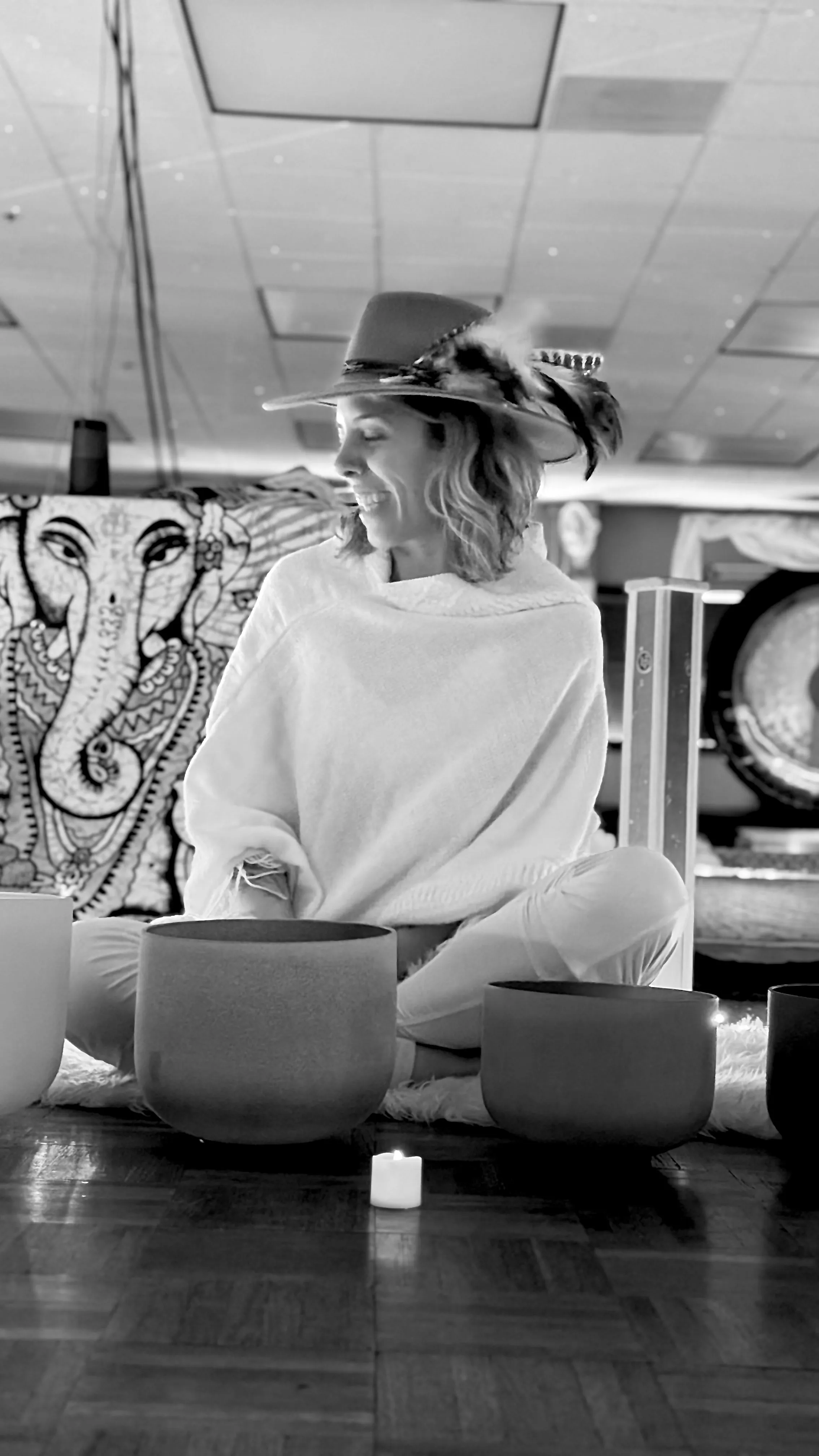 LeeAnna seated with singing bowls in a candlelit space
