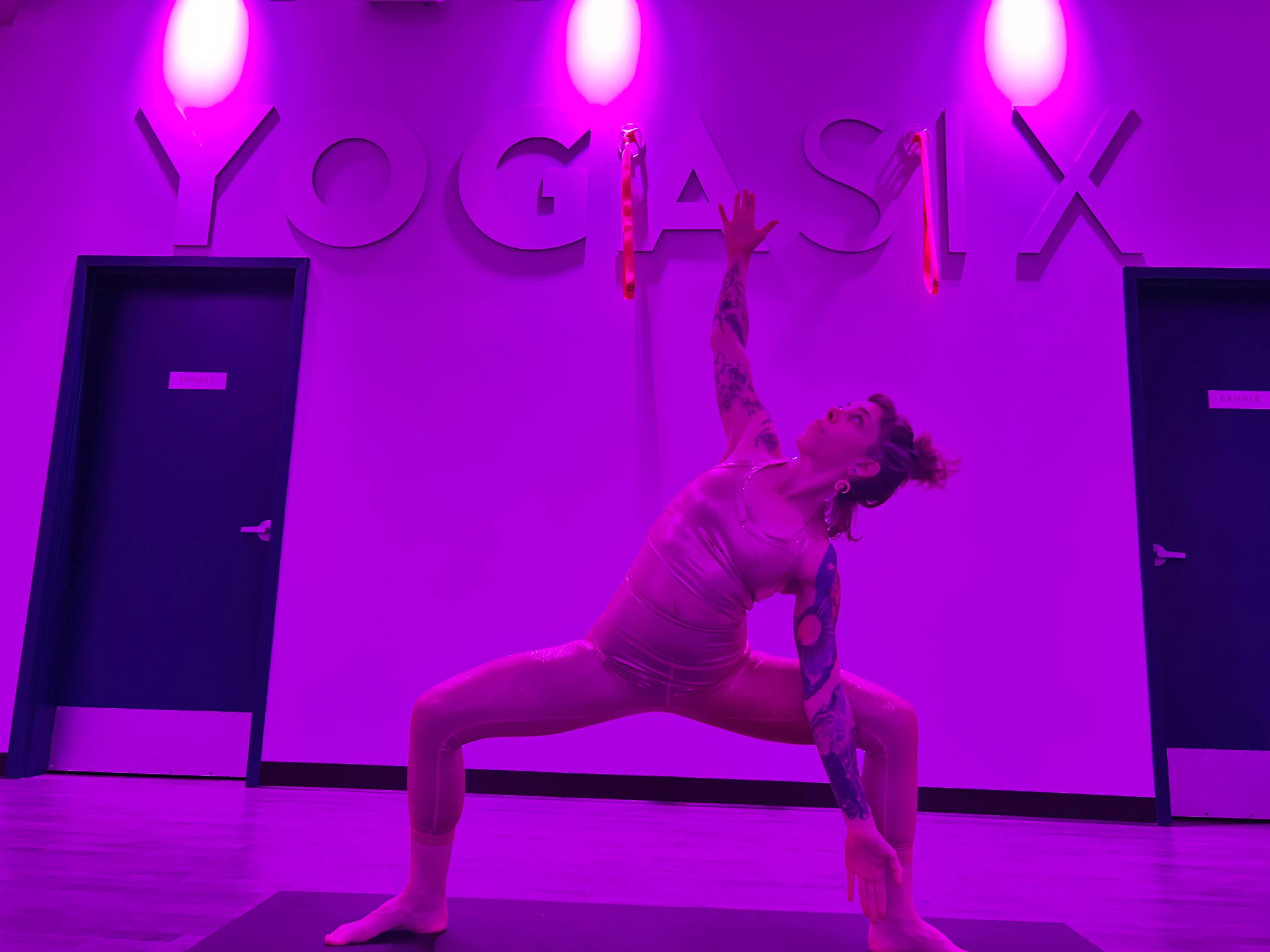 LeeAnna in an extended side angle pose in a purple-lit yoga studio